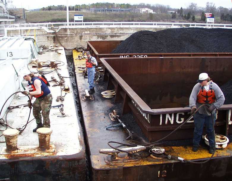 Workers begin attaching cables to the barges to secure them to each other.