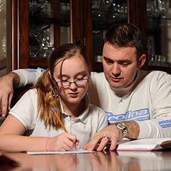 Father and daughter at a table doing homework