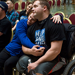 A wife hugging her husband, who is in a wheelchair.