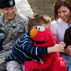 Young boy hugging Elmo while his parents watch