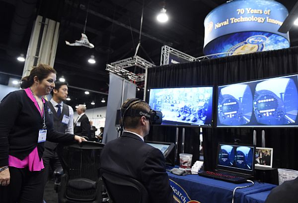 NATIONAL HARBOR, Md. (May 16, 2016) Lauren Burnette, from Space and Naval Warfare Systems Command (SPAWAR) Systems Center Pacific, explains the Battlespace Exploitation of Mixed Reality (BEMR) Lab demo to a visitor at the Office of Naval Research (ONR) exhibit during the 2016 Sea-Air-Space Exposition. BEMR is designed to showcase and demonstrate cutting edge low cost commercial mixed reality, virtual reality and augmented reality technologies and to provide a facility where warfighters, researchers, government, industry and academia can collaborate. U.S. Navy photo by John F. Williams.