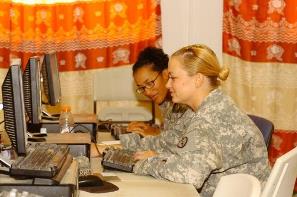 Two soldiers work on computers.