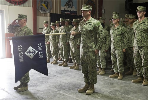 U.S. Navy Senior Chief Petty Officer Jeffery Malia, Naval Mobile Construction Battalion 133 Detail Horn of Africa senior enlisted advisor, holds the guidon during the playing of The Star-Spangled Banner during a transfer of authority ceremony June 24, 2014, at Camp Lemonnier, Djibouti. The NMCB 74 transferred authority to the NMCB 133 after a six month tour of duty. (U.S. Air Force photo by Staff Sgt. Leslie Keopka)