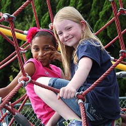 Two young girls sitting together on playground equipment