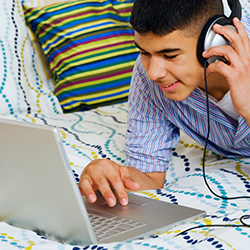 Teen with headphones at laptop computer