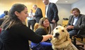 Defense Centers of Excellence for Psychological Health and Traumatic Brain Injury staff members admire Lundy, a service dog, as his owner Jake Young (far right), a former Navy SEAL, looks on. 