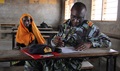 A Kenyan military medic fills out paperwork for a Kenyan woman during a Medical Civic Action Program at Assa, Kenya. During the MEDCAP, Kenyan and U.S. military members, along with non-government organizations, offered physical exams and education on various health issues affecting women and children, including Tuberculosis. (U.S. Army photo by Major Gregg Tooley)