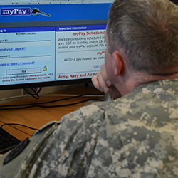 A service member looking at a computer screen with the MyPay website open