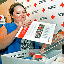 Female at a table sorting through a box of Red Cross informational materials