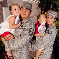 Two military parents each hold their children together in a family portrait