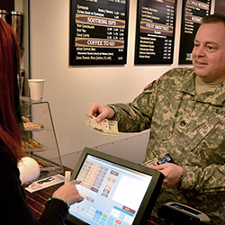 Service member handing cash to a cashier for a purchase.