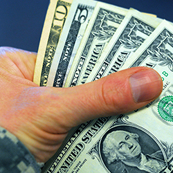 A service member’s hand holding money.