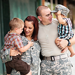 A husband and wife in uniform holding their son and daughter