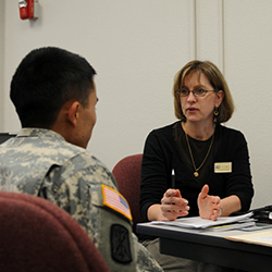 A service member sitting at a table with a woman, talking