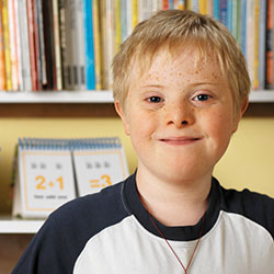 Boy smiling at camera with bookshelves behind him