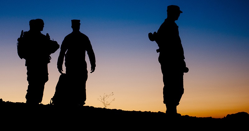 Image of silhouetted Soldiers in front of evening sky