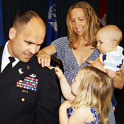 A service member with his daughter and wife who are pinning on his new rank