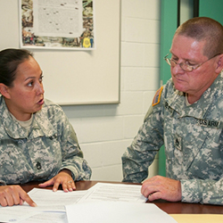 A female and male service members reviewing paperwork in an office.