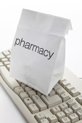 prescription in a pharmacy bag sitting on computer keyboard.