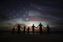 Silhouette of a Family holding hands with a US Flag as background.