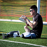 Wounded warrior sitting on soccer field with notebook