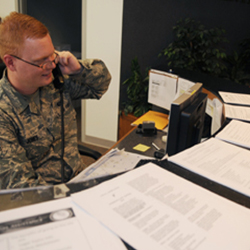 Service member sitting behind a desk answering a phone 