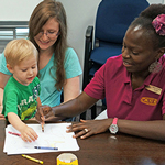 Mother and child sitting at a desk coloring with a service provider.