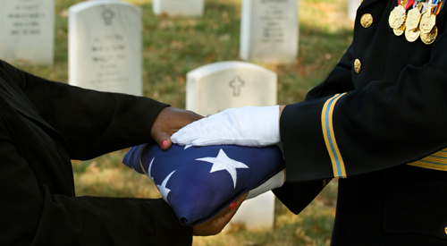 Image of a folder American Flag being handed over to a family member at a VA National Cemetery