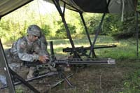 Soldier in shaded tent area works with M2 machine gun