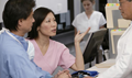 Three healthcare providers stand having a conversation in a medical facility.