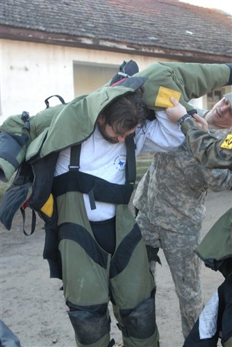 Sgt. 1st Class Kevin Vanklompenberg, operations sergeant, 745th Explosive Ordnance Disposal Unit, Task Force Falcon, Multinational Battle Group East, helps Arian Mavrigi, teacher at the Kamenice/Kamenica youth center, put on a bomb suit during a unexploded ordnance class Jan. 18 at the youth center. (U.S. Army photo by Pfc. Brian J. Holloran, 130th Public Affairs Detachment, Connecticut National Guard)