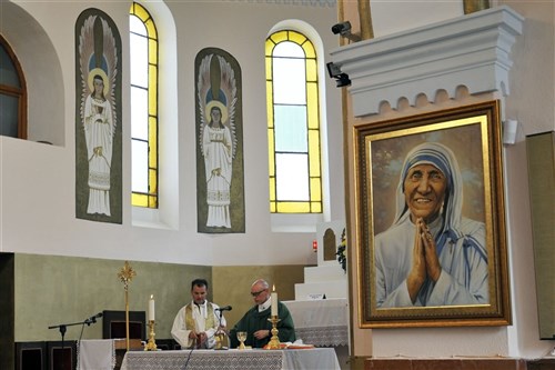 LETNICA/LETNICE, Kosovo &mdash; A painting of Mother Teresa hangs beside the altar at the Shrine of the Black Madonna in Letnica/Letnice as Army Chap. (Capt.) Timothy Meier, Los Altos, Calif., and the church&#39;s priest, Don Christe, conduct a mass for NATO Kosovo Force soldiers June 12. (U.S. Army photo by Sgt. 1st Class Michael Hagburg)
