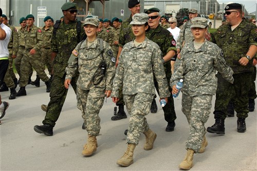 Spc. Sheena Leno, Driscoll, N.D., Sgt. Christina Sung, Montclair, Calif., and Spc. Shanna Leno, Mandan, N.D., march with Danish and Turkish troops during the memorial march at Camp Bondsteel, Kosovo, June 6.