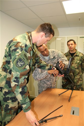 GRAFENWOEHR, Germany- Sgt. Anthony Woods, squad leader, A Company, 1st Battalion, 2nd Infantry Regiment, teaches the Serbian Soldiers how to disassemble and reassemble the M249 Squad Automatic Weapon. (U.S. Army Photo by Spc. Bethany L. Little)