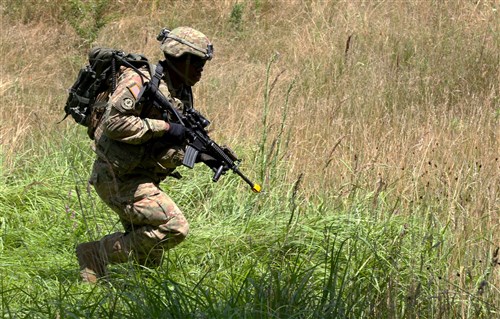 Sgt Dalvin Carr, an infantryman assigned to Alpha Company, 1st Battalion, 41st Infantry Regiment, 2nd Infantry Brigade Combat Team, through a heavy patch of brush during day one of the Multinational Battle Group-East's Best Warrior Competition on Camp Bondsteel, Kosovo, July 9.  (U.S. Army photo by: Staff Sgt. Thomas Duval, Multinational Battle Group-East Public Affairs)