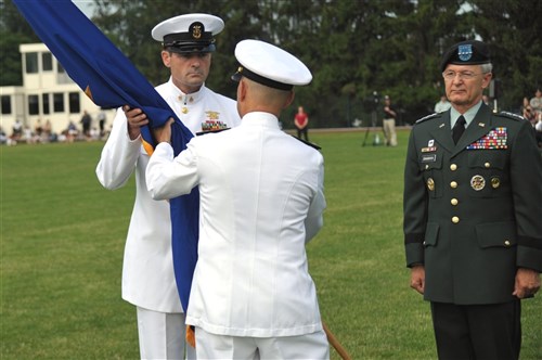 STUTTGART, Germany   (Left to right) Navy Fleet Master Chief Roy Maddocks, U.S. European Command (USEUCOM) Senior Enlisted Leader, takes the guidon from Navy Adm. James Stavridis, (USEUCOM) Commander, during a ceremony on Patch Barracks here June 30. Stavridis, who replaced Army Gen. John Craddock, will also assume responsibilities as Supreme Allied Commander, Europe, from Craddock in a ceremony July 2 in Mons, Belgium. (Department of Defense photo by Richard Herman)