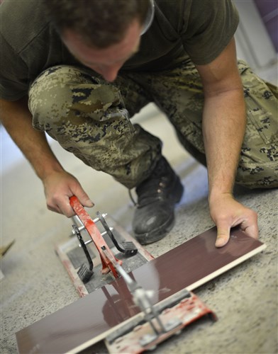 A Croatian Army member cuts a piece of tile before attaching it to a bathroom wall at an elementary school in Ogulin, Croatia, June 27, 2014. The school bathrooms are being renovated by Airmen from the 133rd and 148th Civil Engineering Squadron, and 219th Red Horse Squadron in partnership with the Croatian Army. Croatia is a Minnesota State Partner under the National Guard State Partnership Program. 