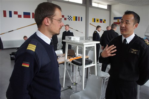 Lt. Cmdr. Justin Hsu, lead exercise planner for U.S. Naval Forces Europe-Africa/U.S. 6th Fleet, speaks with German navy Cmdr. Jens Herfurth, lead exercise planner for Germany, during BALTOPS 2013, the 41st annual combined maritime forces exercise in the Baltic region. The exercise is designed to improve interoperability among the participating forces to support regional stability.