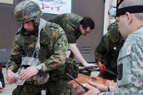 U.S. Army Staff Sgt. John Lacroix, with the 421st Multifunctional Medical Battalion, instructs a Bundeswehr soldier on the proper procedure to care for a simulated casualty at the Viper Pit in Wiesbaden, Germany, May 12. The Viper Pit teaches combat life saver skills and then tests the trainees on what they have learned by placing them in a stressful scenario where they have to rescue and treat victims while "under fire."