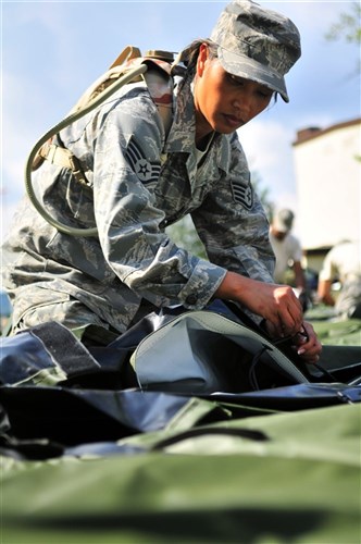 RAMSTEIN AIR BASE, Germany &mdash; Air Force 86th Medical Group technician Staff Sgt. Glenda Castillo ties strings used to connect sides of a tent designed to house up to ten patients during set up of the Ramstein Mobile Aeromedical Staging Facility training site, Aug. 2-6. Each member of the MASF is part of an elite group of volunteers who man the MASF positions on a two-year basis, knowing as combatant commander enablers they are expected to deploy with only 24 hours notice. (U.S. Air Force photo by Tech. Sgt. Michael Voss)