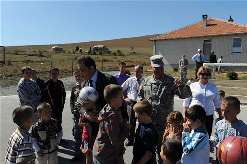 Col. Francisco J. Neuman, Multinational Battle Group East commander, and Bajrush Ymeri, mayor of Novoberde/Novo Brdo, Kosovo, are swarmed by students ready to play their first game after to a ribbon cutting ceremony for a new sports field and improvements to Asdreni school.  Col. Neuman, of Ponce, Puerto Rico, is a member of the Puerto Rico National Guard. (Sgt. Joshua Dodds, 130th Public Affairs Detachment)