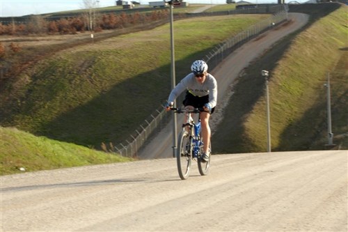 Spc. Carlos Ruiz, Gurabo, Puerto Rico, an infantryman with A Company, 1st Battalion, 296th Infantry Division, Multinational Battle Group East, climbs a hill while cycling near the perimeter of Camp Bondsteel, Kosovo Dec. 2. Ruiz regularly competes in triathlons and mountain bike races while at home in Puerto Rico. He continues to train for them while deployed to Kosovo as part of the NATO-led peacekeeping mission here. 