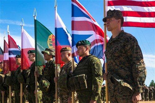 U.S. Marine Sgt. Steven Mashburn, a squad leader with Black Sea Rotational Force, right, holds the American flag during the opening ceremony for Exercise Saber Strike at the Pabrade Training Area, Lithuania, June 8, 2015. The exercise brings NATO and other partner nations together for a multilateral training event designed to promote regional stability and security, strengthen partnerships, and foster trust.  (U.S. Marine Corps photo by Sgt. Paul Peterson/Released)