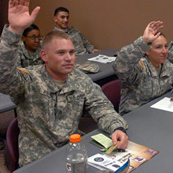 Service members raising hands in a class.