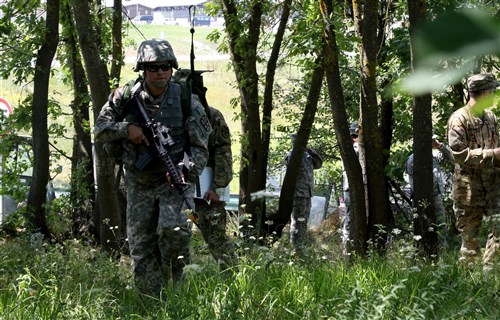 Spc. Autumn Ladines, a crew chief with the Arizona National Guard deployed to Kosovo with the Multinational Battle Group-East's Southern Command Post, navigates through a tree line during the Multinational Battle Group-East's Best Warrior Competition held on Camp Bondsteel, Kosovo, July 9. (U.S. Army photo by: Staff Sgt. Thomas Duval, Multinational Battle Group-East public affairs)