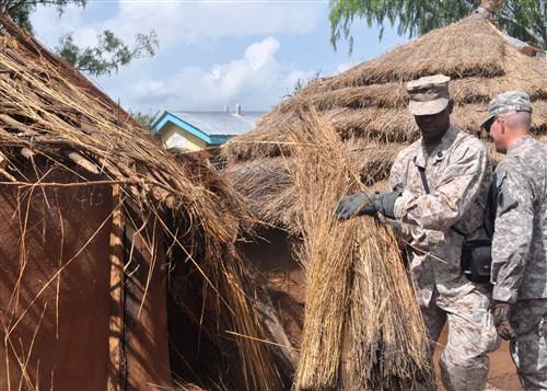 THIES, Senegal - Marine Master Gunnery Sergeant Joel Rogers moves grass off an old hut in preparation for building a new hut for orphans in Uganda, June 26, 2012. A joint team of U.S. Army, Navy, and Marines personnel recently teamed up for a 10-day community relations project at an orphanage in Uganda's remote Karamoja region. The team, which was joined by about 50 local residents, helped construct 16 grass-thatched houses for the Moroto Childcare and Orphanage Project in Nakapelimen Village. (Photo courtesy of U.S. Mission Uganda)