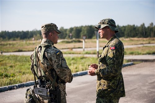 A Canadian Combat Engineer talks to a Ukrainian Observer Controller during day two of the situational training exercise lanes at Rapid Trident 2014. Rapid Trident is an annual U.S. Army Europe-conducted, Ukrainian-led multinational exercise designed to enhance interoperability with allied and partner nations while promoting regional stability and security.