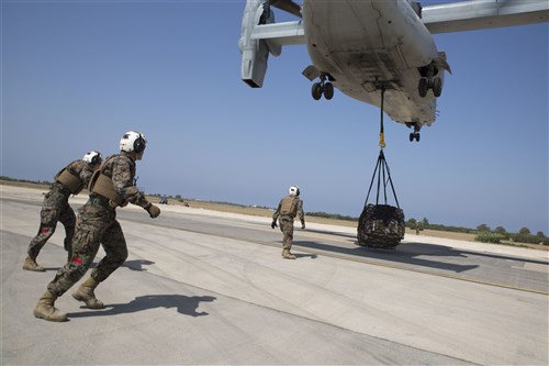 Landing support specialists with Combat Logistics Battalion 2, Special Purpose Marine Air-Ground Task Force-Crisis Response-Africa, brace themselves against rotor wash as an MV-22B Osprey picks up a 1,098 pound pallet of Meals, Ready to Eat during a helicopter support team exercise aboard Naval Station Rota, Spain, July 6, 2016. External lift training prepares the Marines to efficiently attach cargo to the aircraft and helps qualify air crew in the mission-essential task of rapid insertion and extraction in a possible crisis response scenario. (U.S. Marine Corps photo by Staff Sgt. Tia Nagle/Released)