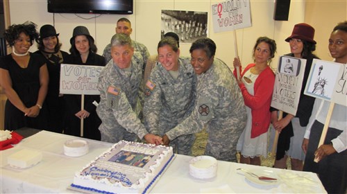 Brig. Gen. Jody Daniels, Col. John Stack, and Command Sgt. Maj. Lynice Thorpe cut a cake at the Women's Equality Day celebration at Patch Barracks. 