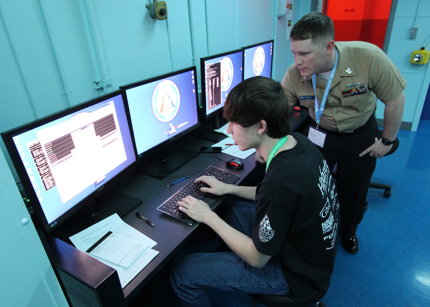 Information Systems Technician 1st Class Kyle Gosser, an instructor at the Center for Information Dominance Unit Corry Station, mentors a local high school student participating in the inaugural Cyberthon competition at the National Flight Academy at Naval Air Station Pensacola during the weekend of Jan. 23-25. The Cyberthon competition tests student teams on their abilities to use the computer skills they learned in their classrooms to defend and defeat cyber attacks on websites. U.S. Navy photo by Ed Barker.